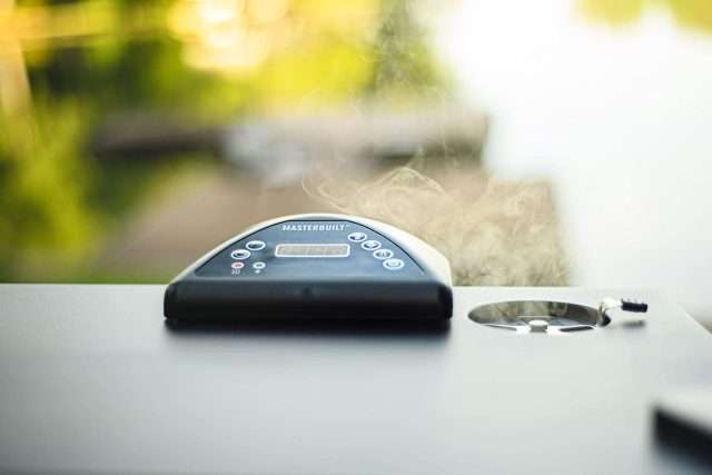 Masterbuilt digital electric smoker cooking with smoke coming out of smoke vent
