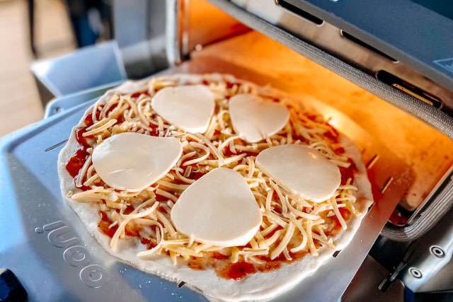 Launching a pizza into the Ooni Volt 12 using perforted peel
