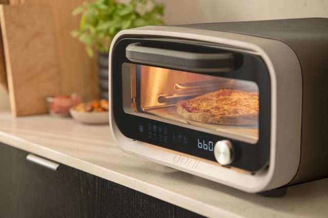Ooni Volt 2 Sitting on countertop cooking a pizza