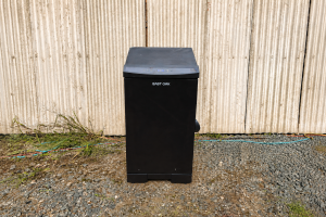 East Oak Electric Smoker sitting in front of sheds